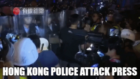 Police officers using their long shields to push and charge the reporters away violently