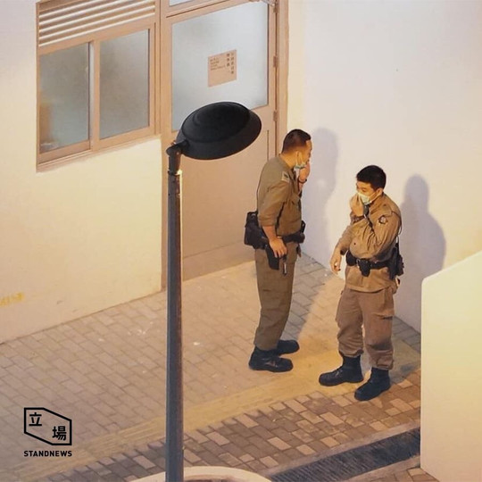 Police officers smoke on duty while waiting for arrivers at quarantine camp